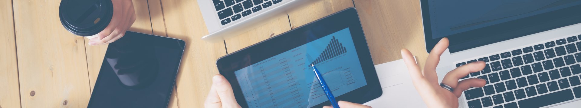 Generisches B&uuml;ro, mehrere H&auml;nde die &uuml;ber einen Tisch greifen Laptops und Tablets auf dem tisch